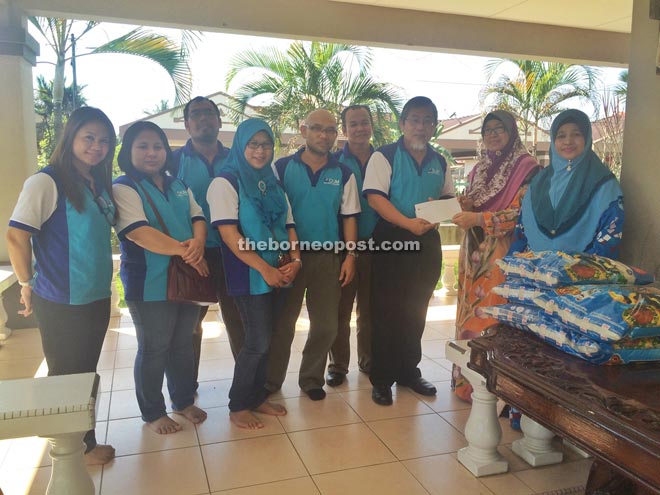 Abdullah (third right) handing over a cheque to Aini in presence of Siti Khadijah (right) and the team from OUM.