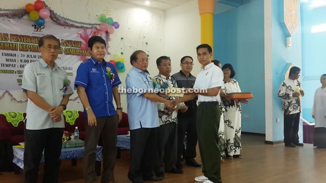 Nyalau (third left) presents the incentive to one of the 111 eligible students from Engkilili. Also seen is Rayong (second left).