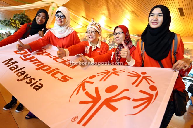 ENCOURAGEMENT: Minister of Welfare, Women and Family Development Datuk Fatimah Abdullah (second left), Kuching Special Olympics Chapter chairman Datin Dayang Mariani Abang Zain (third left) and coach Ruhana Bujang (second right) flashing the thumbs-up to special athletes from Sarawak participating in the World Summer Games in Los Angeles from July 25 to Aug 2 prior to their departure at the Kuching International Airport yesterday. With them are two of the athletes from Kuching. — Photo by Muhammad Rais Sanusi