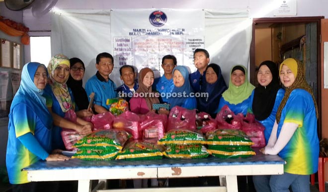 Khairunisa (sixth from left) presents the contributions to a recipient, while Ishak (fourth from left) and members of the Neighbourhood Women Committee look on. 