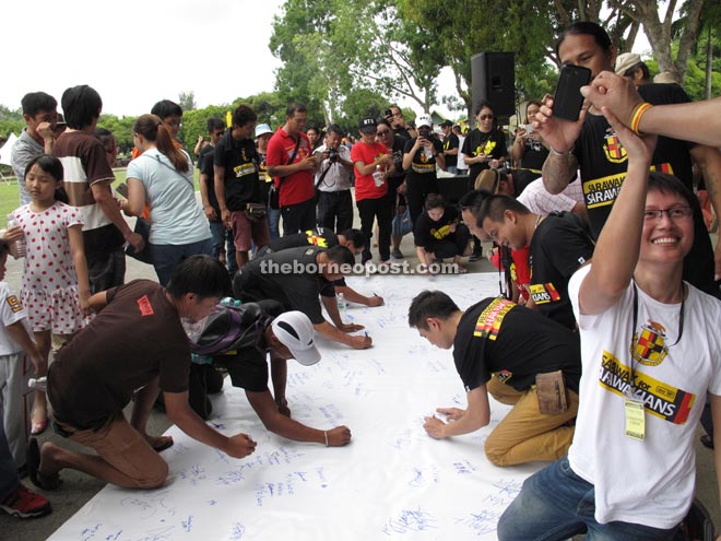 Participants sign a banner to show their support for the gathering