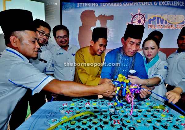 Masni (fifth left) officiating at the event by cutting the ribbon while Marzuki (fourth left) and others look on.