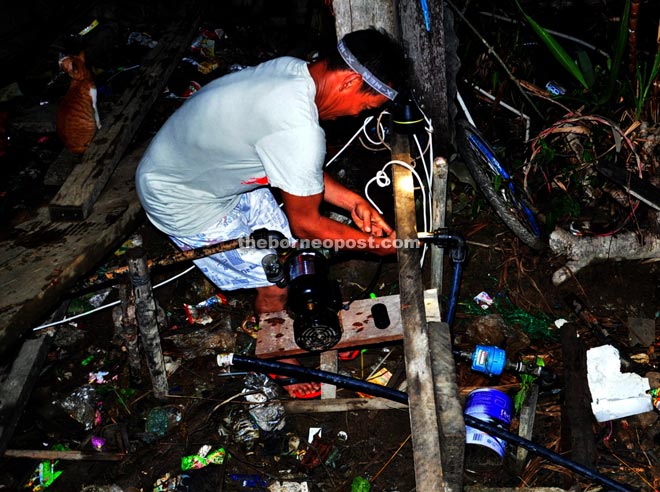 A man works through the night to fix a water pump used to pump the murky salty river water.