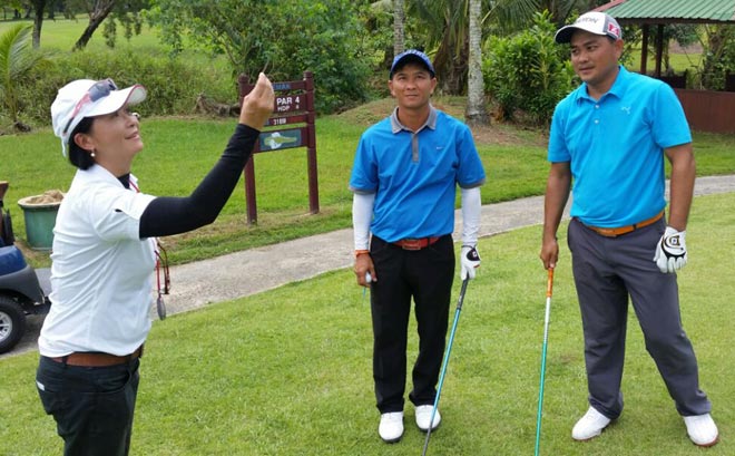 Lee Ka Tung (centre) and younger brother Kah Ching are all smiles as match official June Yii toss the coin before the start of the play-off at the 27th Sarawak Classic golf championship at KGS last Sunday. 
