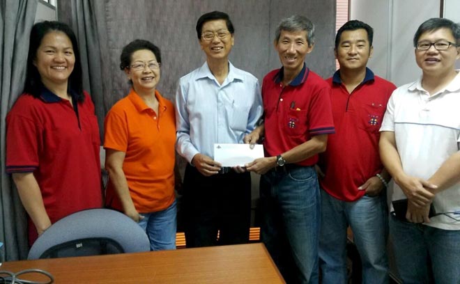 Lee (right) hands over the sponsorship to Ho (fourth right) while (from left) Angela Chan, CHMS No. 3 Alumni Association vice president Hii How Dee and others look on.