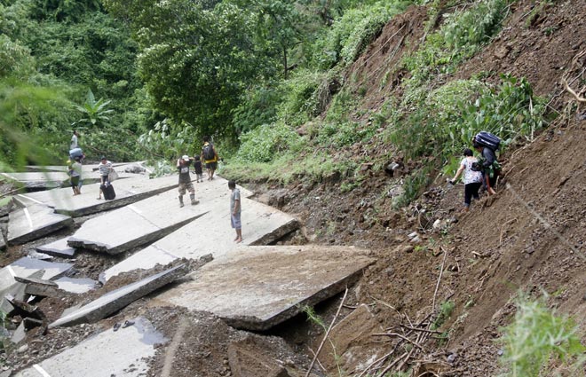 Residents cross a mountainside temporary road after a portion of the national highway was destroyed by landslides due to heavy rains brought about by typhoon Goni, in Lidlidda town, Ilocos sur province, northern Philippines. — AFP photo