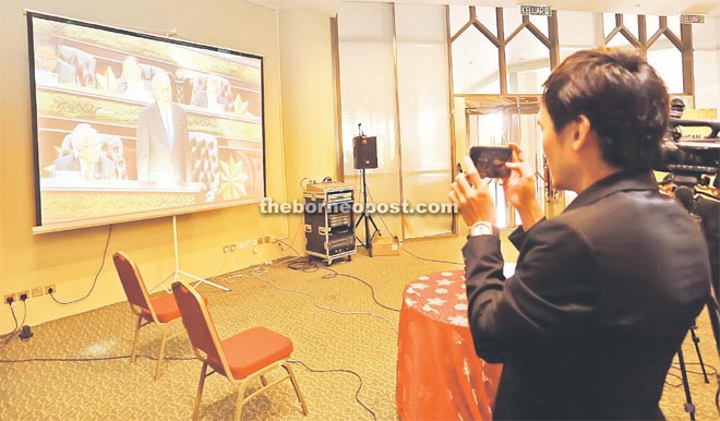 A pressman tries to screen-shoot the image of Adenan on the projector’s screen in the complex’s media room. The chief minister is seen here delivering his speech at the start of one-day DUN sitting. — Photo by Muhammad Rais Sanusi