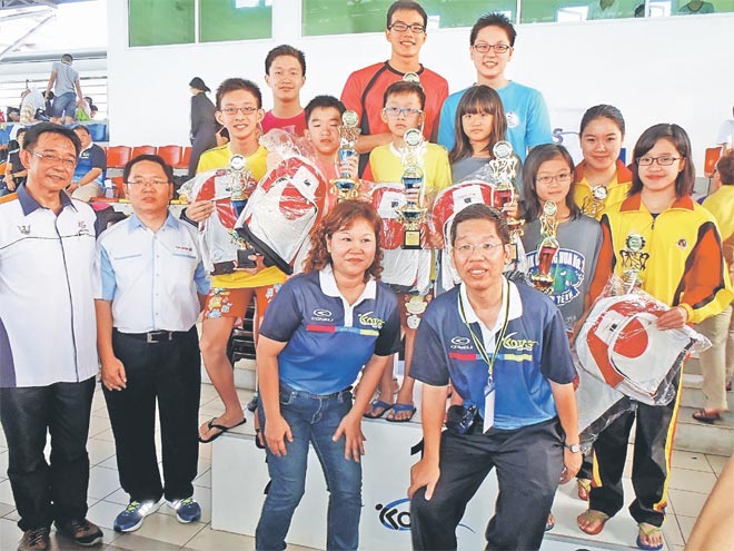 Assistant Minister of Housing Datuk Abdul Karim Hamzah (left), Fuji Xerox Printers business development manager (Sabah, Sarawak & Brunei) Lee Poh Fatt (second left), Chai (right, front) and event advisor Alice Kwon posing with the best boys and girls swimmers after the prize presentation.