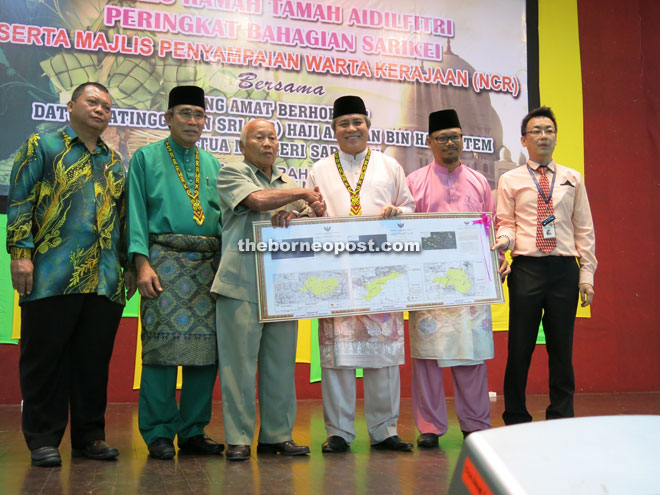 Awang Tengah(fourth left) presents the government gazette for perimeter surveyed NCR land to Penghulu Kasa while (from left) Dahim, Len, Ibrahim and Ngu look on.