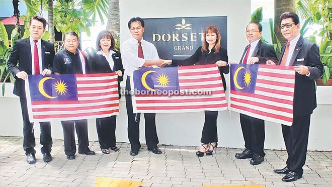 Matteri (fourth left) handing over the flag to Susan. Also seen are the hotel associates and the department officer.