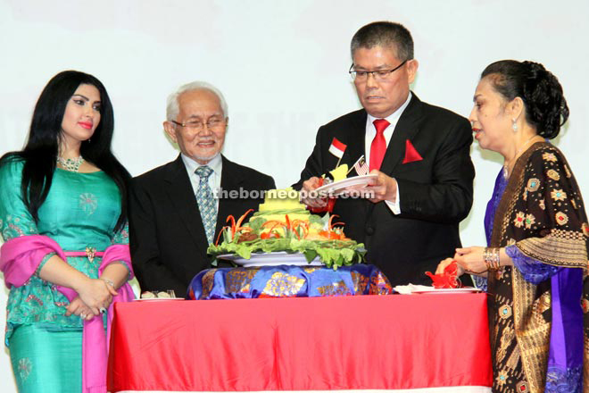 Jahar cutting the ‘tumpeng’, an Indonesian delicacy, during his country’s Independence Day reception last night before serving a piece to the Head of State. Looking on are Ragad (left) and Jahar’s wife Loriana Gultom.  — Photo Muhammad Rais Sanusi