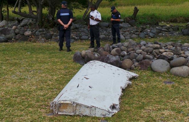 French gendarmes and police stand near a large piece of plane debris which was found on the beach in Saint-Andre, on the French Indian Ocean island of La Reunion recently. — Reuters photo