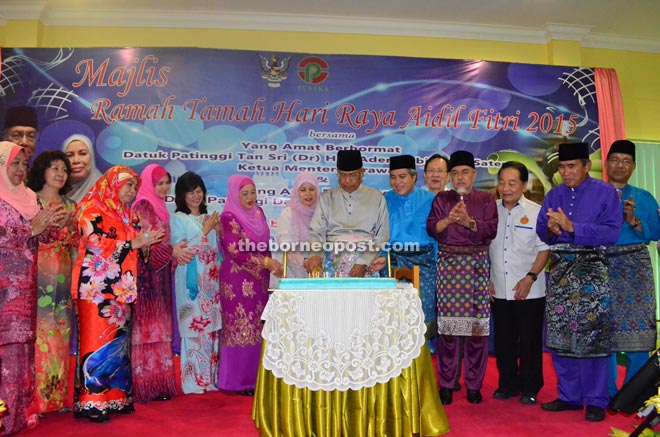 Adenan and Jamilah cut a cake at the Hari Raya gathering. 