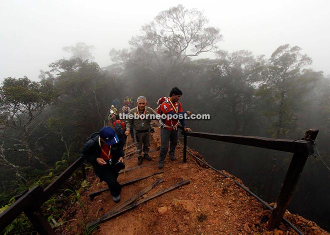 Members of the first team to climb Mount Kinabalu since its closure crossing a newly rebuilt trek that was damaged by the 6.0 magnitude quake early June. Also seen is Sabah Parks chairman Datuk Tengku Adlin Tengku Mahamood (second right).