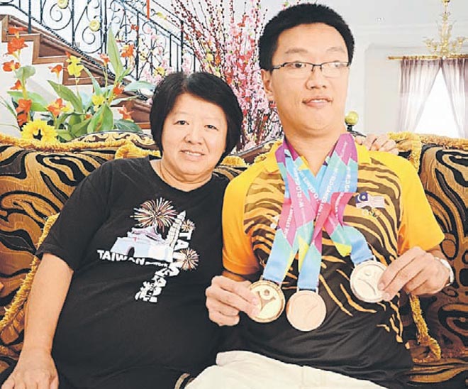 Toh (right) with his mother showing the medals he won at the prestigious Special Olympics World Summer Games held in Los Angeles recently.
