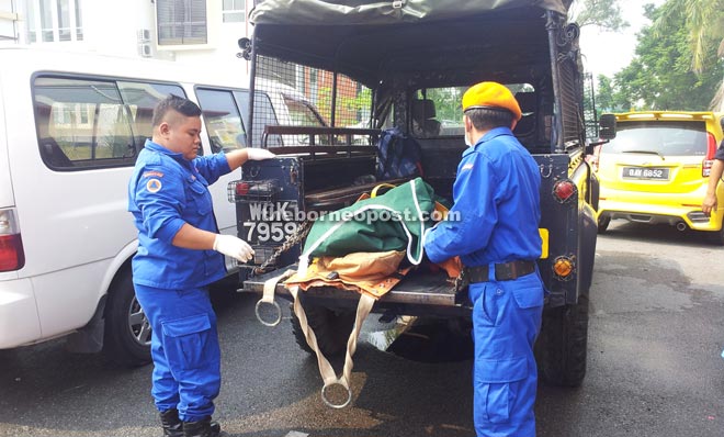 Civil Defence Department personnel load the body of the unidentified man for transportation to the mortuary.