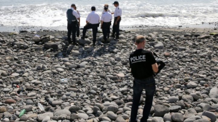 Police officers inspect metallic debris found on a beach in Saint-Denis on the French Reunion Island in the Indian Ocean on August 2, 2015, close to where where a Boeing 777 wing part believed to belong to missing flight MH370 washed up last week -© AFP/File / by Marianne Barriaux 