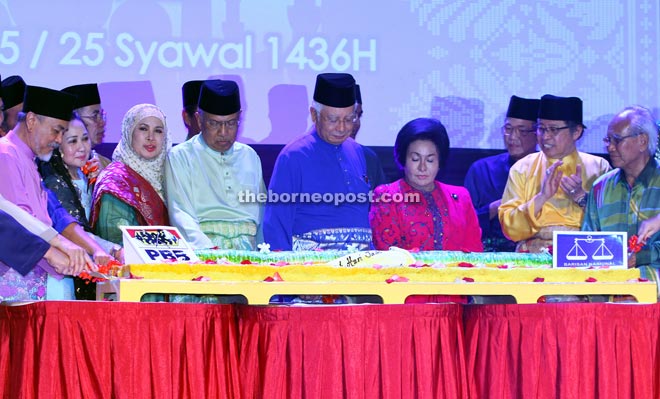 Najib (centre) cutting the ‘pulut kuning’ which was presented as a belated birthday surprise to him at the PBB Kuching Zone Ramah Tamah Aidilfitri at the Borneo Convention Centre Kuching (BCCK) last night. With him are (from third left, front) Jamilah, Adenan, Rosmah, Abang Johari and Jabu. — Photos by Chimon Upon