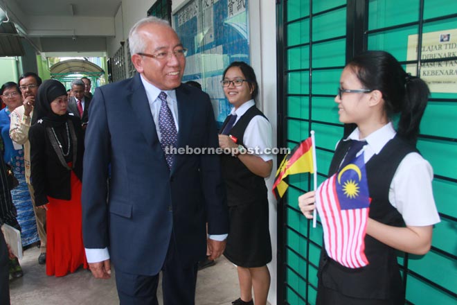 Mahdzir walks past smiling students during a tour of the school premises.