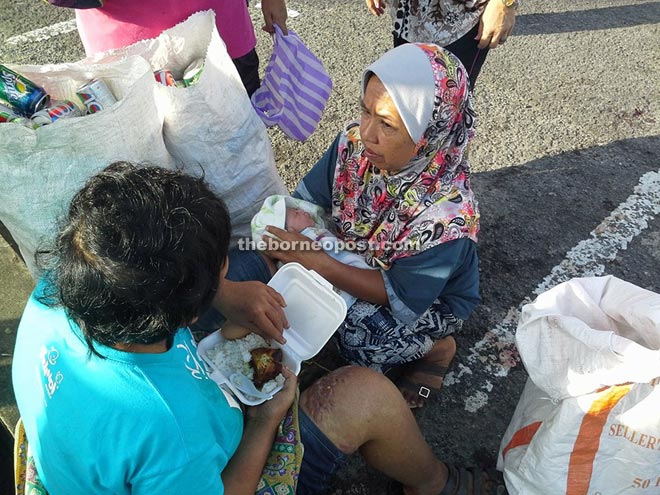 A member of the public holds the baby while its mother tucks into a meal.