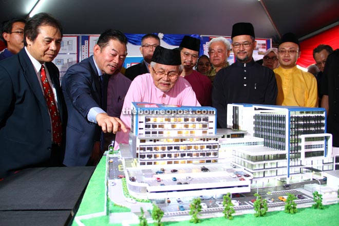 Taib (centre) takes a closer look at the scale model structure of the new KPJ Kuching Specialist Hospital. He is accompanied by  Dr Jerip (left), Kamaruzzaman (fourth left) and Amiruddin (second right). — Photo by Chimon Upon 
