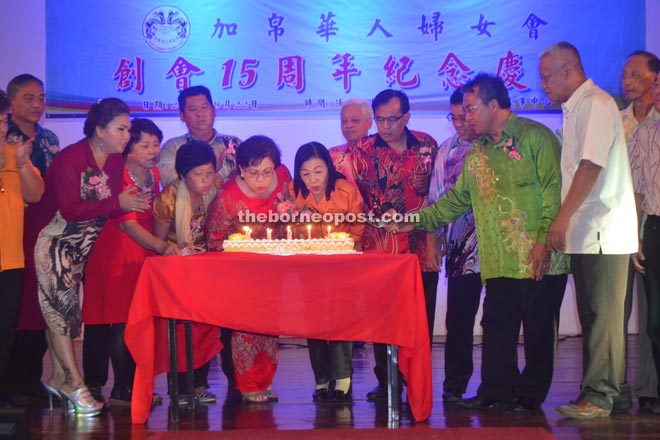 Doris (fourth left) and Wong blow out the candles before cutting the anniversary cake.