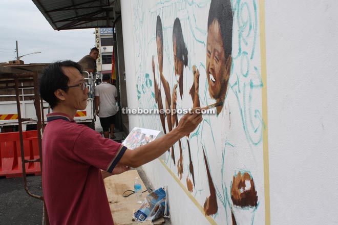 Chee works on the Kapit’s first mural, which depicts three children brushing their teeth. 