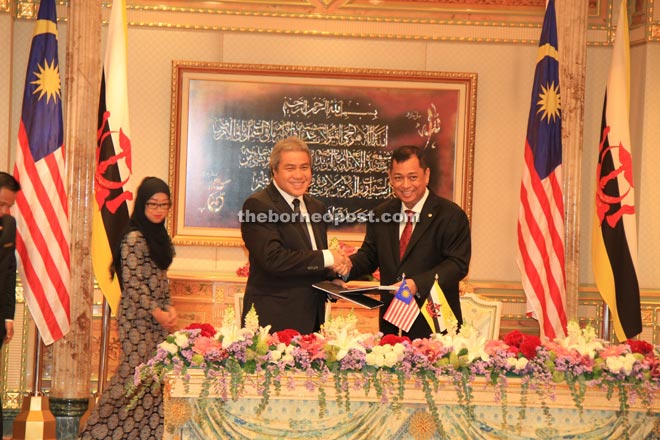 Awang Tengah (left) and Awang Haji Mohammad Yasmin exchanging documents of collaboration signed at the end of the bilateral meeting in Brunei.