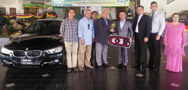 Daud (fourth right) and Hasweera (third right) handing over the mock car key for the BMW 320i car to Ghanie (fourth left) -- for an ace at Matang Hole 8 and Siol Hole 6 -- while the organising committee and others look on.