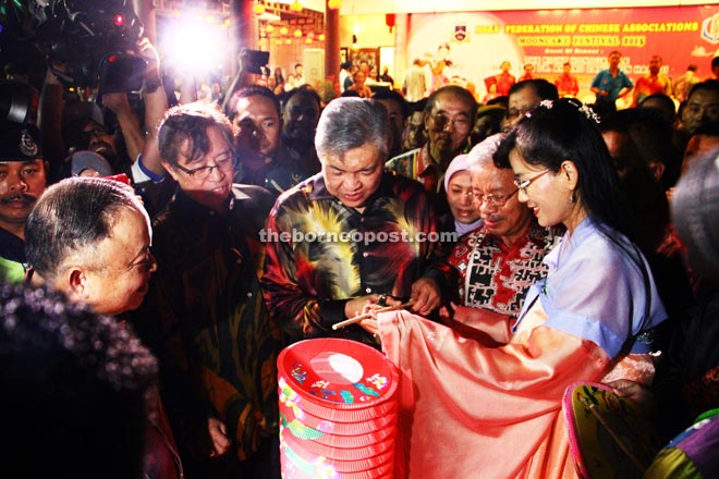 Zahid (centre) admiring a red lantern before lighting it to mark the celebration. Also seen (from left) are Chan, Abang Johari, Nancy and Masing (second right). — Photo by Chimon Upon