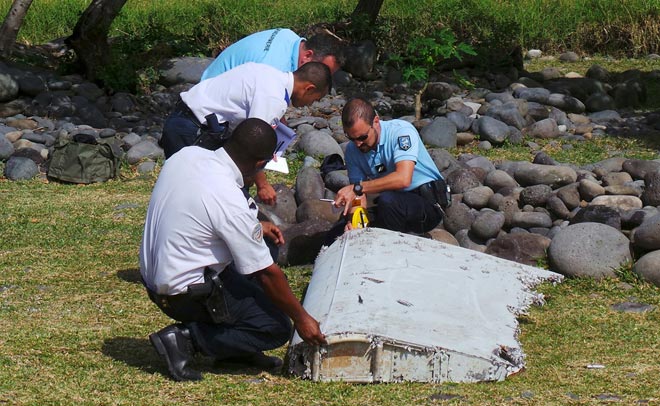 File picture shows French gendarmes and police inspecting a large piece of plane debris which was found on the beach in Saint-Andre, on the French Indian Ocean island of La Reunion, July 29. — Reuters photo