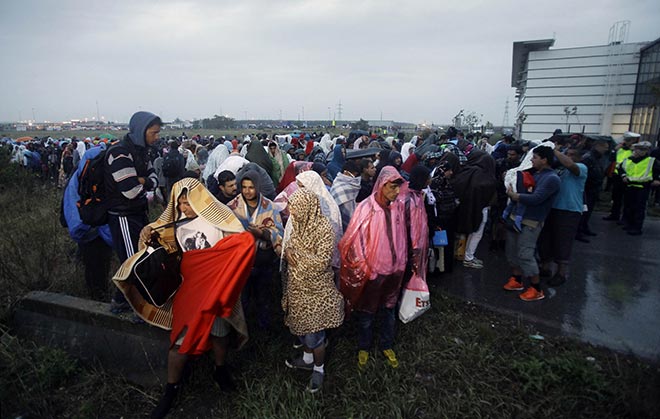 Migrants cross the Hungarian-Austrian border on foot after their arrival into a transit zone by public bus to the Hungarian border, between Hungarian Hegyeshalom and Austrian Nickeldorf. — AFP photo