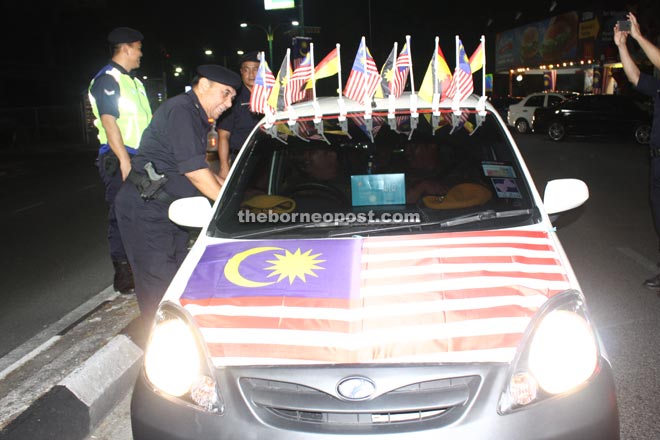 ACP Roslan greeting a motorist at one of the roadblocks set up on the eve of National Day during ‘Ops Bersepadu’ on Sunday night.
