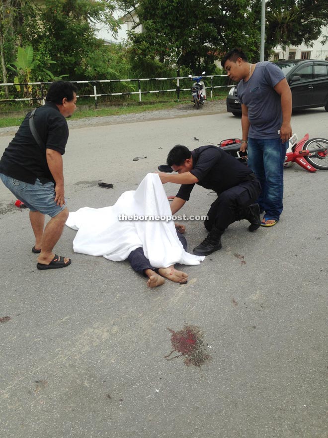 Members of the public watch as a police patrolman checks the deceased for personal documents.