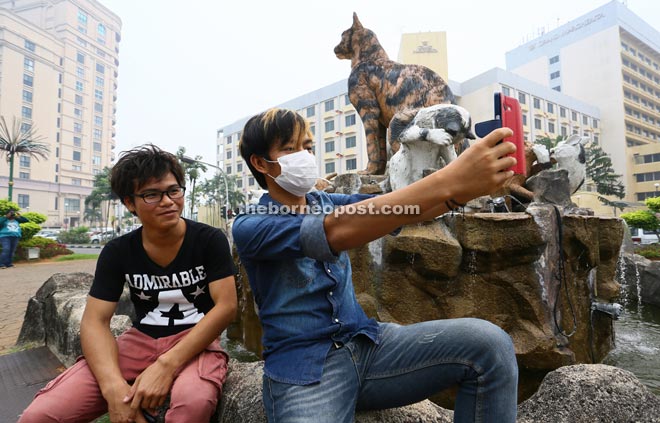 Two young men taking a selfie at the Jalan Tunku Abdul Rahman cat statues. — Photos by Muhd Rais Sanusi 