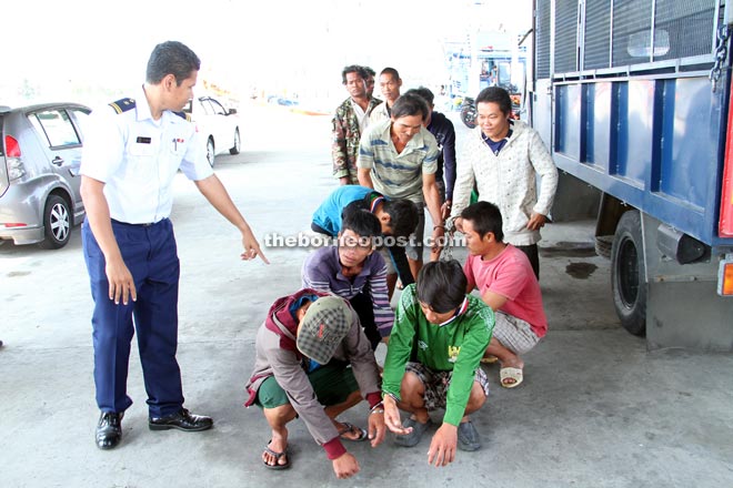 An MMEA officer (left) with some of the detained foreign nationals.