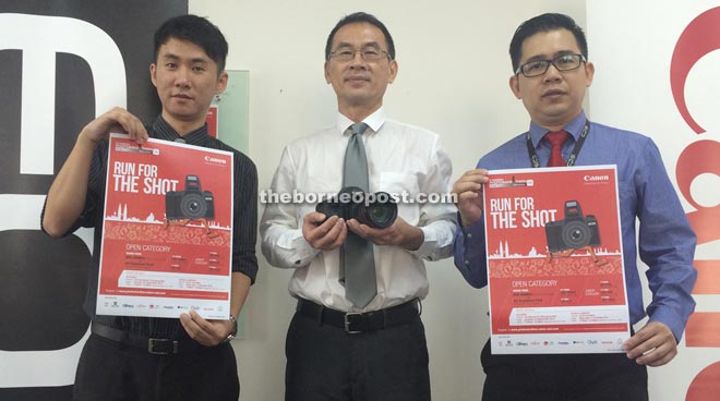 Ho (centre) holding the grand prize of a Canon EOS 5S Mark III DSLR camera. With him are Zhng (left) and Tia.