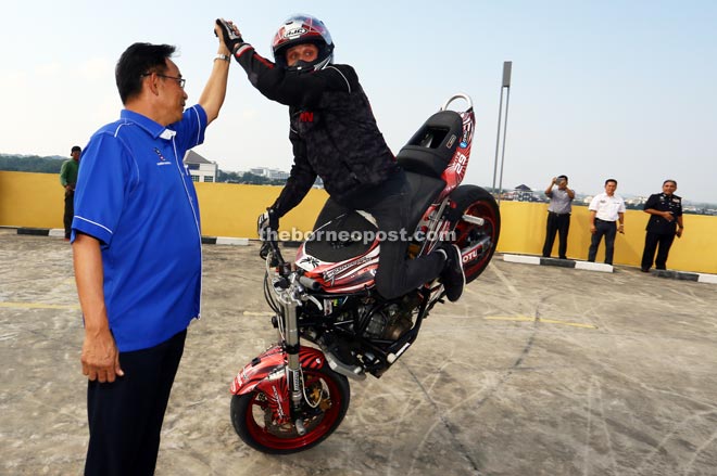 Twite high-fives Abdul Karim while performing a stunt during a preview at CityONE Megamall in Kuching. Twite, a seasoned and multi-XDL stunt riding champion will be performing at KIBW this weekend. — Photo by Muhammad Rais Sanusi