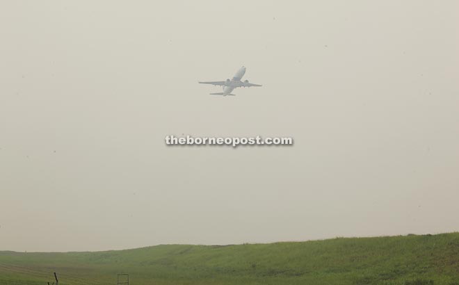 A plane takes off from Kuching International Airport (KIA) into the hazy sky.