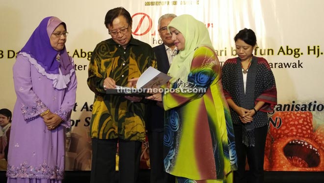 A delegate from Singapore (right) briefs Abang Johari about the book that she presented to the minister as souvenir. Looking on is Dr Yasmin (left).