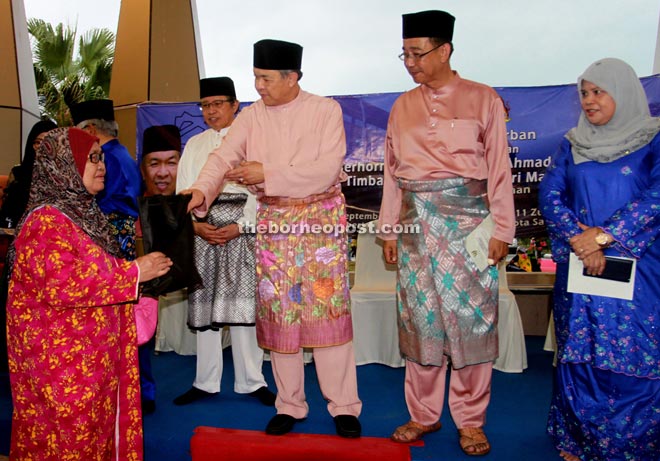 Zahid, flanked by Abdul Karim (second right) and Abang Johari, presents the meat to a villager, as Rubiah (right) looks on.