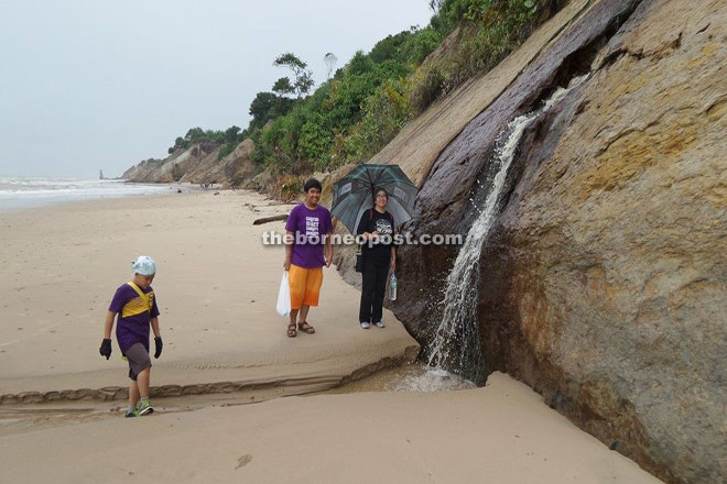 Visitors stop by a waterfall at the beach. 