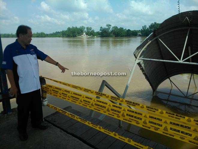 Jinep checks on the sunken pontoon in Bintangor town, which has been sealed off for refloating works. 