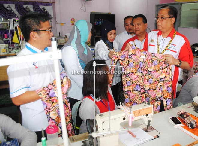 Ismail Sabri (right) takes a look at the Baju Kurung done by a student during his visit to the sewing class at GiatMara. He is accompanied by Nangka assemblyman Dr Annuar Rapaee (left) and Nanta (second right).    