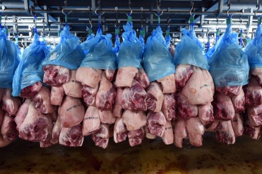 © AFP/File | A file photo taken on March 8, 2015 in Brennilis, western France, shows pork hanging at a salting plant 