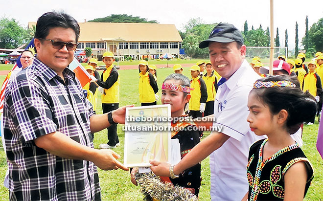 PENGHARGAAN:  Ellron (kiri) menyampaikan sijil penghargaan kepada kontinjen SK Banjar diketuai oleh guru besar Jinli Ramle.