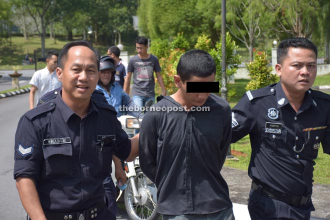 Policemen escort Hairi to the courthouse after he was captured across the road from the courthouse.