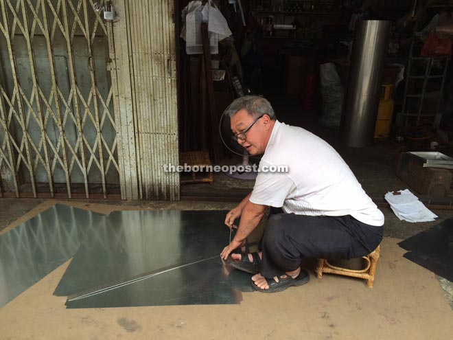 Ho Chin Hin carves products from a tin sheet.