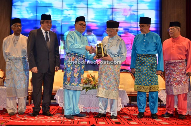 Kipli (third left) presents Taib (third right) with a token of appreciation, while (from left) Daud, Awang Tengah, Asfia and Putit look on.