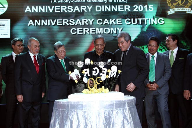 Adenan (centre) prepares to cut the cake to celebrate Harwood’s 30th anniversary at the dinner. The chief minister is flanked by Bujang (on his right) and Awang Tengah. 
